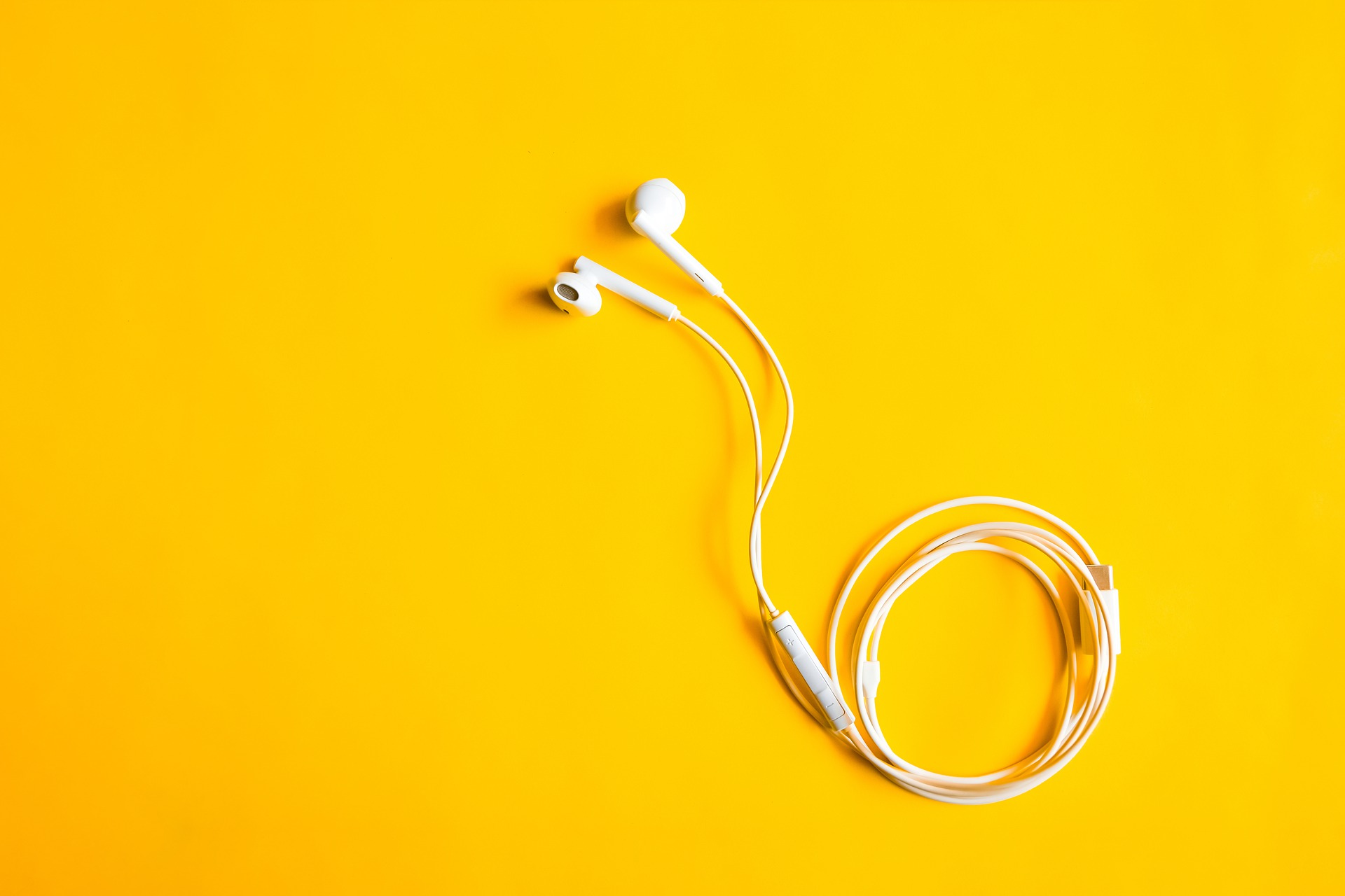 White earbuds on yellow backdrop